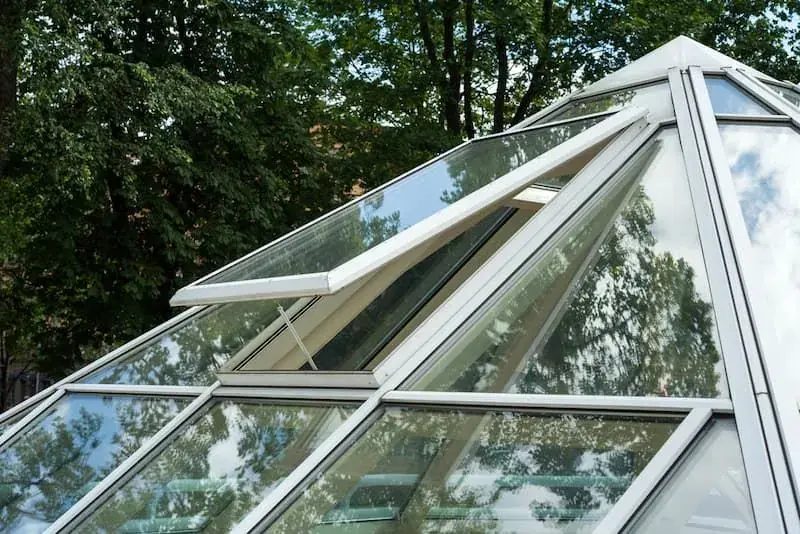 Angled view of a glass roof canopy framed by trees